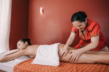 asyalı masör spa salonunda kadına ayak masajı yapıyor 