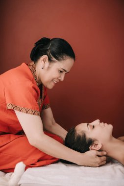 spa salonunda kadına boyun masajı yapan asyalı masör yan görünümü 