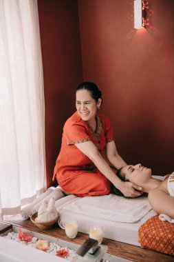 gülümseyen asya masör spa salonunda kadına boyun masajı yapıyor 