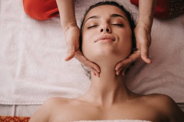 spa salonunda kadına yüz masajı yapan masör kırpılmış görünümü 