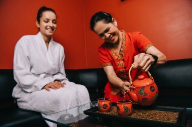 asya masör fincan ve bornoz çekici kadın spa gülümseyen çay döken 