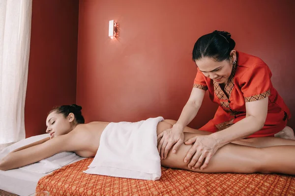 asian masseur doing foot massage to woman in spa salon