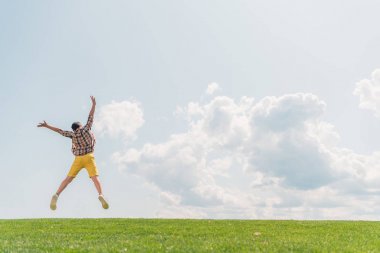 mavi gökyüzüne karşı çocuk atlama ve gesturing geri görünümü 