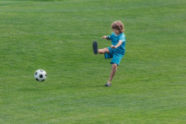 yeşil çim üzerinde futbol oynayan spor kıvırcık çocuk 