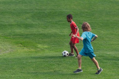 çim üzerinde futbol oynayan sevimli çok kültürlü çocuklar 