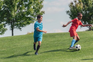 yeşil çim üzerinde futbol oynayan sevimli çok kültürlü çocuklar 