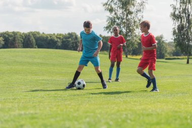 yeşil çim üzerinde futbol oynayan sevimli çok kültürlü arkadaşlar 