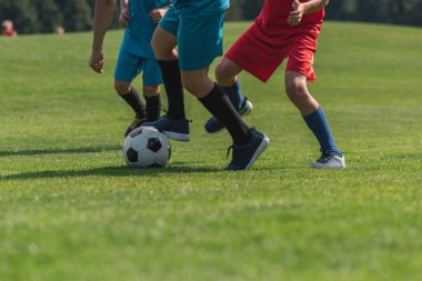 çim üzerinde futbol oynayan üç çocuk kırpılmış görünümü 