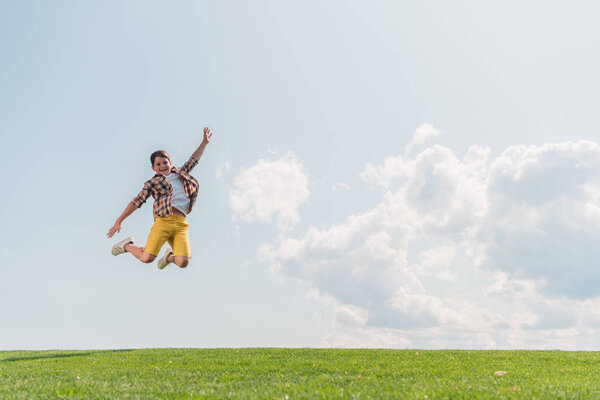 happy boy jumping and gesturing against blue sky 
