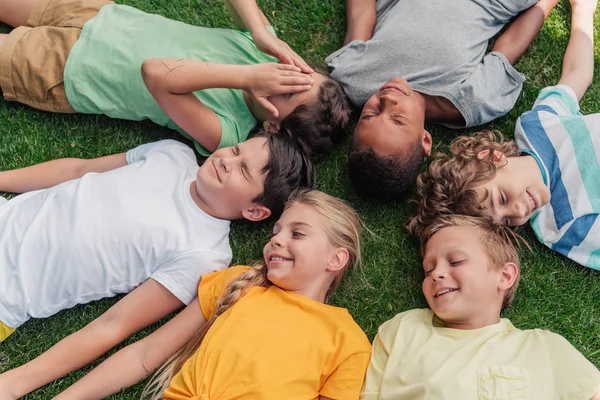 躺在草地上的快乐多元文化孩子的头顶视图 — 图库照片