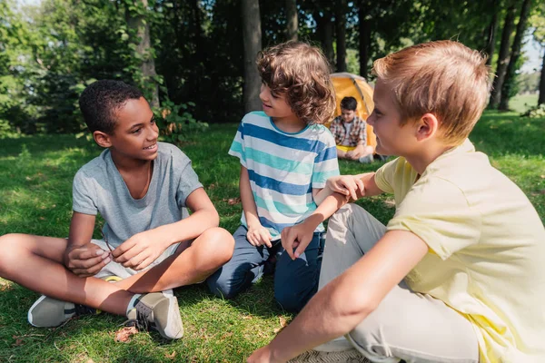 Selective Focus Multicultural Boys Smiling While Sitting Grass — Stock Photo, Image