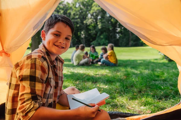 Selective Focus Cheerful Boy Holding Notebook Camp — Stock Photo, Image