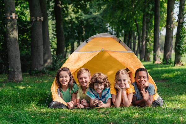 Crianças Multiculturais Felizes Sorrindo Enquanto Deitado Perto Acampamento — Fotografia de Stock