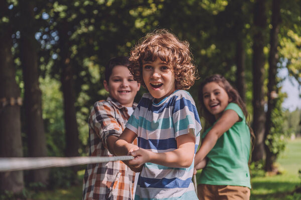 selective focus of cheerful kids competing in tug of war 