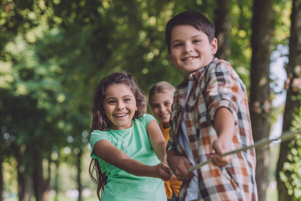 selective focus of positive kids competing in tug of war 