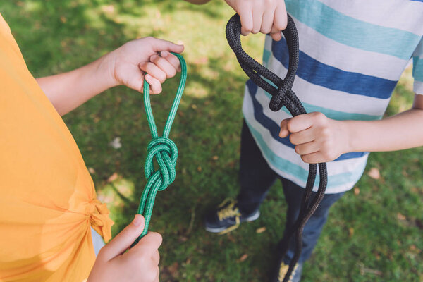 cropped view of kids holding ropes outside 