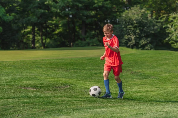 happy kid in sportswear running while playing football 