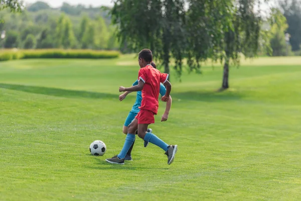african american boy playing football with friend 