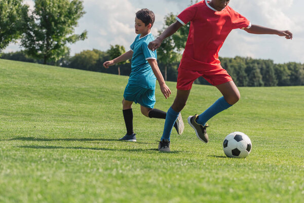 cropped view of african american kid playing football with friend 