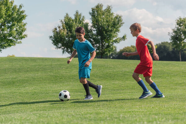 friends in sportswear playing football on green grass 