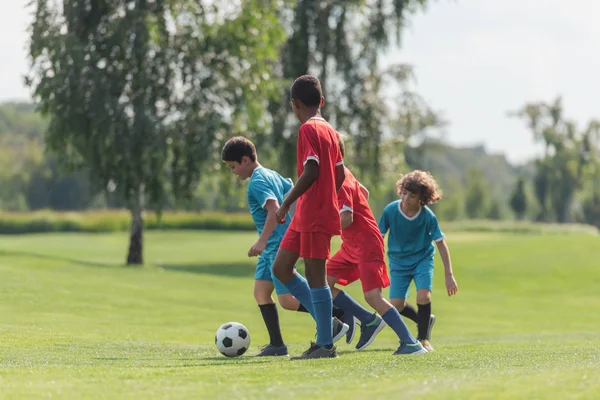 cute kids playing football with african american friend 
