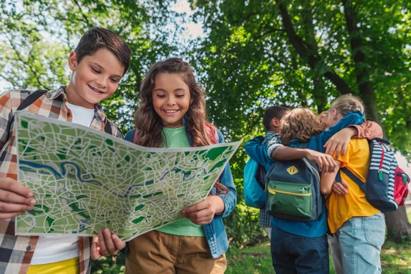 Enfoque Selectivo Niños Felices Mirando Mapa Cerca Amigos Multiculturales Abrazándose —  Fotos de Stock