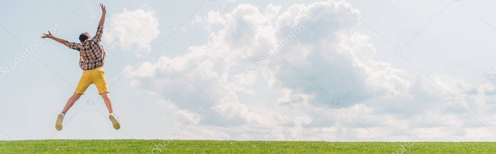 panoramic shot of boy jumping and gesturing against blue sky 