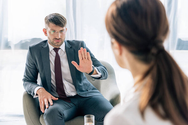 selective focus of handsome businessman in suit and glasses talking with journalist 