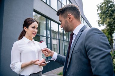 mikrofon tutan gazeteci ve resmi giyim iş kadını ile konuşurken 