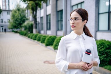 resmi giyim mikrofon tutan çekici gazeteci ve uzağa bakıyor 