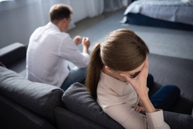 pensive upset couple in living room at home clipart