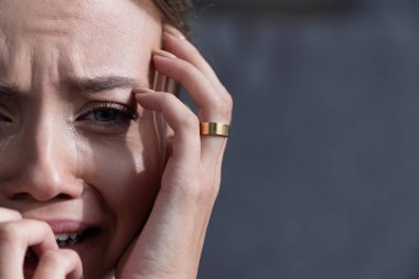 partial view of upset young woman with ring crying and looking at camera clipart