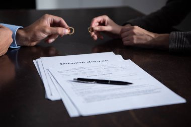 partial view of couple at table with divorce documents holding rings clipart
