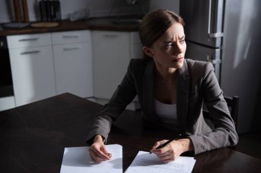 sad young woman at table with divorce documents clipart