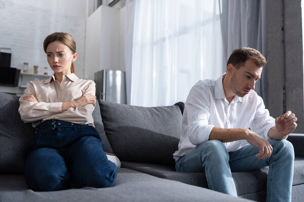 pensive upset couple in living room at home