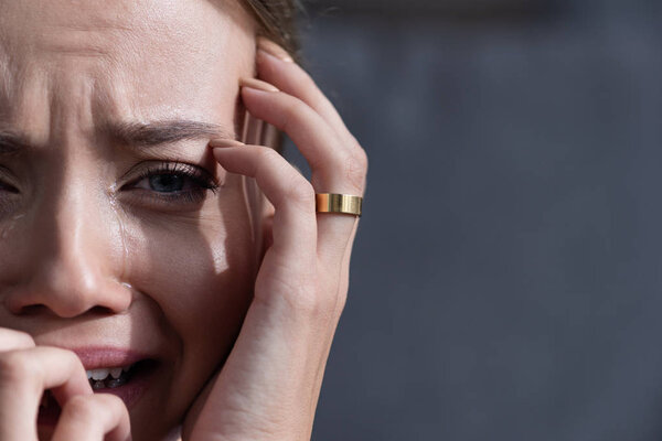 partial view of upset young woman with ring crying and looking at camera