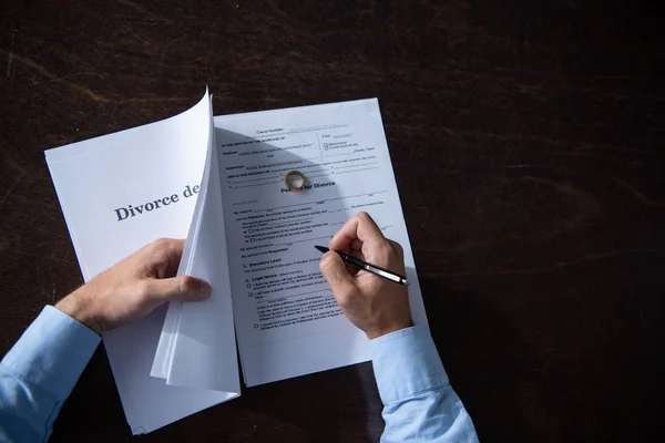 男子坐在桌旁并签署离婚文件的片面看法 — 图库照片