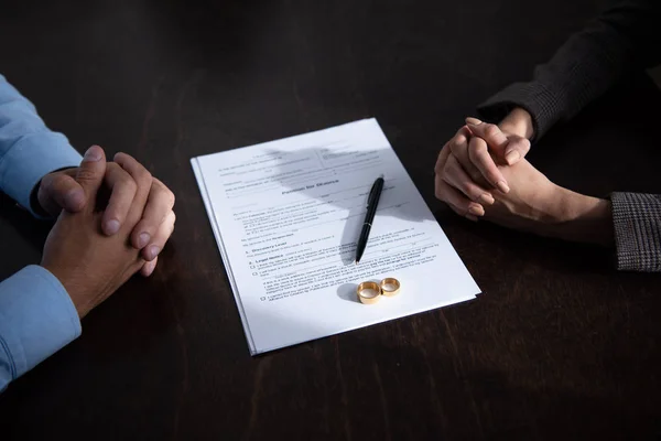 Partial View Couple Sitting Table Clenched Hands Divorce Documents Rings — Stock Photo, Image