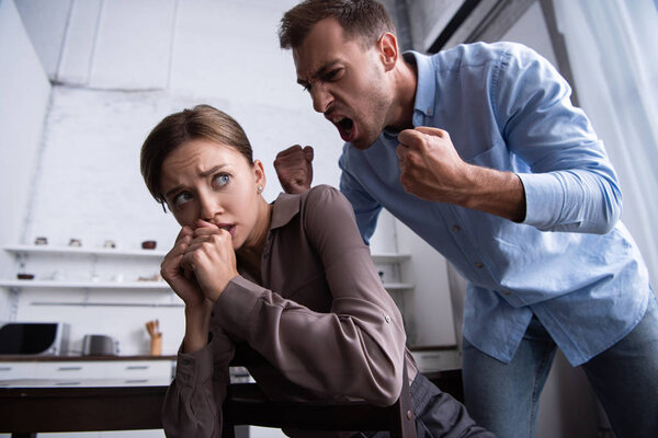 aggressive man holding fists up and yelling at scared wife