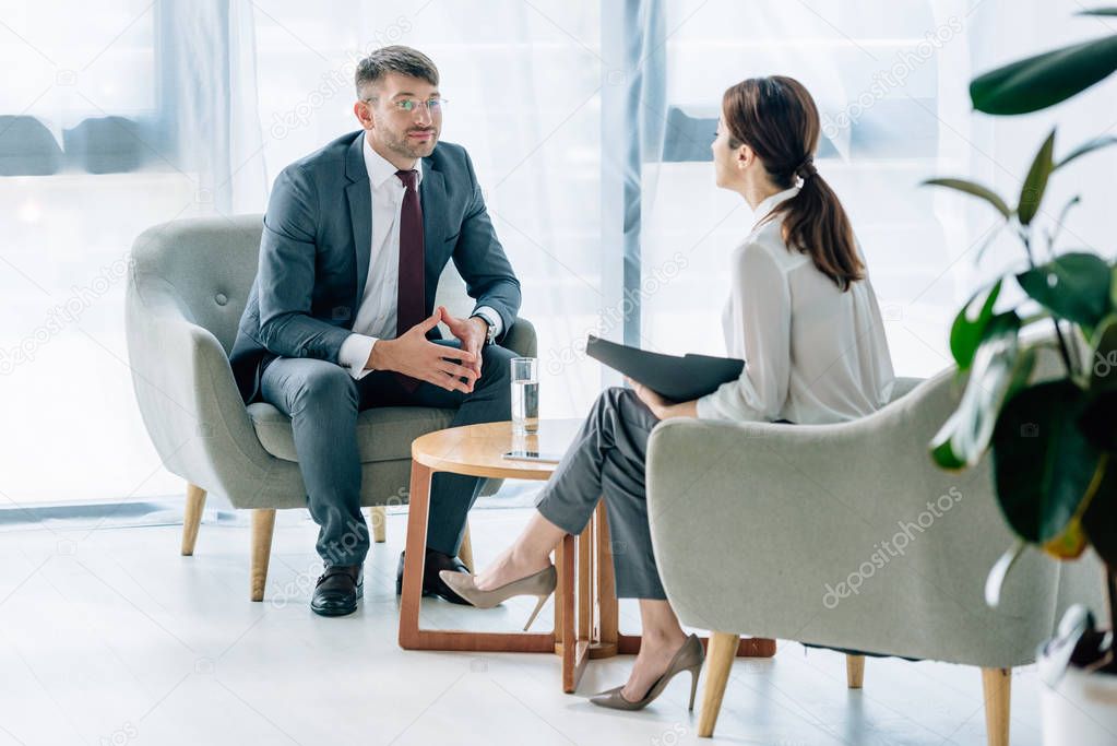 handsome businessman in suit and glasses talking with journalist 