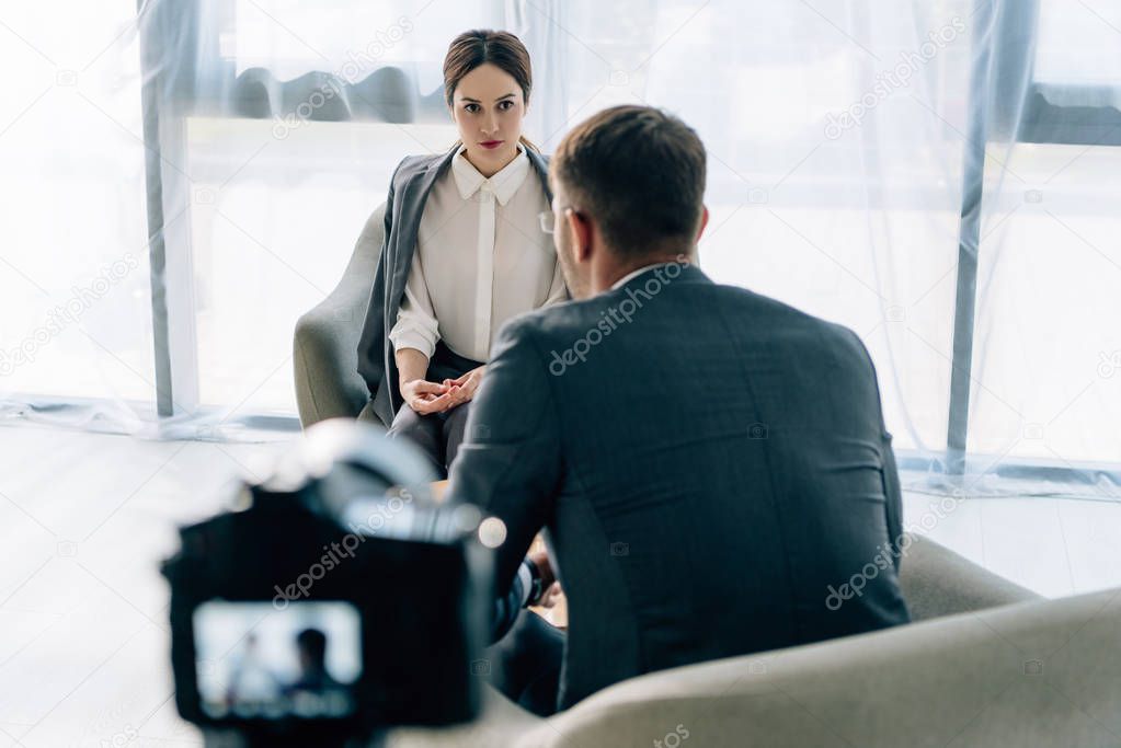 selective focus of attractive journalist talking with businessman in formal wear 
