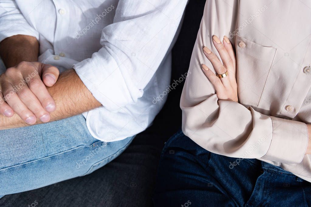 partial view of woman and man with crossed arms