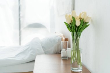 klinikte vazo, cam ve şişelerde ahşap masa üzerinde lalelerin seçici odak noktası 