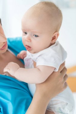 hastanede çocuğunu tutan genç anne kırpılmış görünümü 