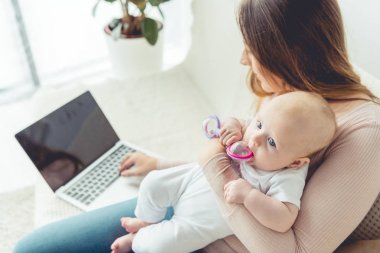 anne çocuğunu tutarak ve dairede kopya alanı ile dizüstü bilgisayar kullanarak 