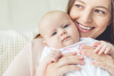 çekici ve gülümseyen anne dairede çocuğunu tutarak 