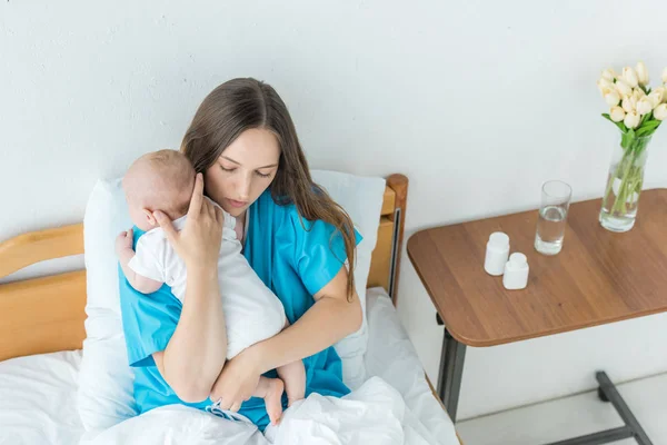 病院で子供を抱く魅力的で若い母親の高い角度の眺め — ストック写真