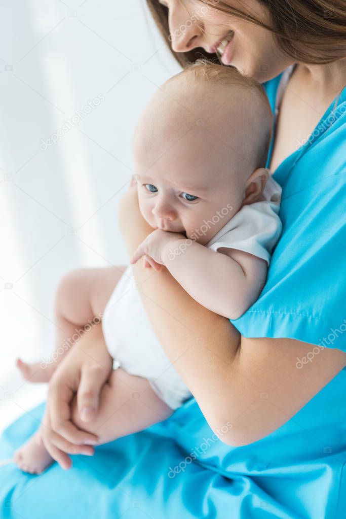 cropped view of young mother holding her child in hospital 