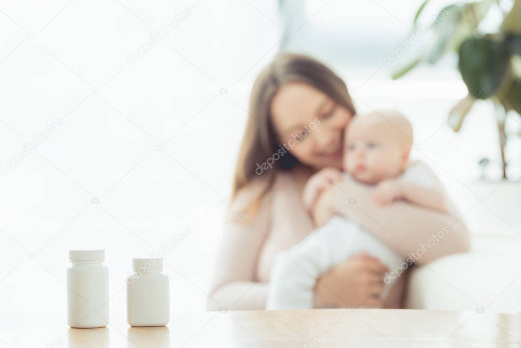 selective focus of white bottles with pills on wooden table 