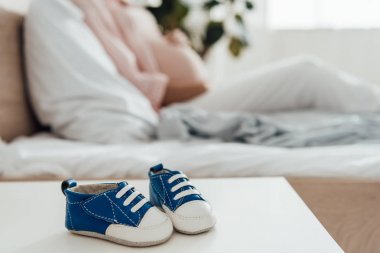 ön planda hamile kadın ve bebek ayakkabıları seçici odak
